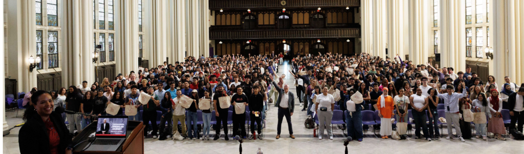 Shepard Hall at CCNY filled with over 500 students smiling at the camera