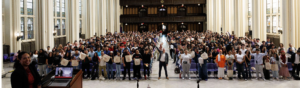 Shepard Hall at CCNY filled with over 500 students smiling at the camera